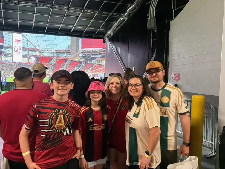 A picture of Will and his family posing for a photograph near the soccer field.