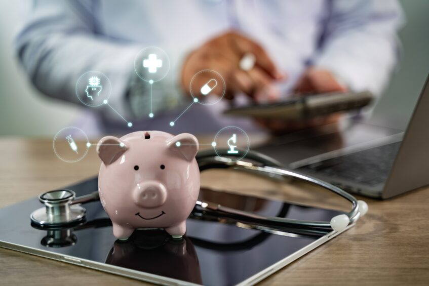 Piggy bank with healthcare icons and a stethoscope on a tablet, symbolizing data-driven financial decisions in behavioral health.