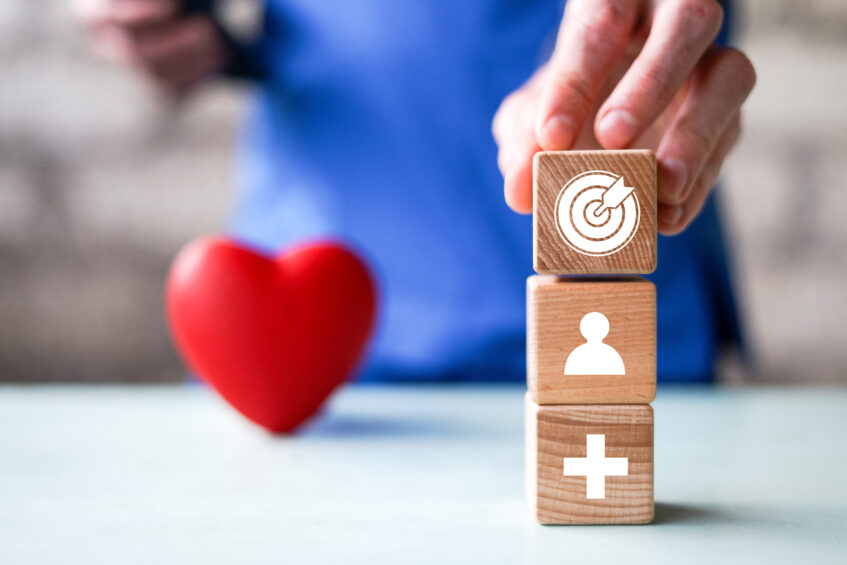 Stacked wooden blocks with healthcare and leadership icons beside a heart, symbolizing technology strategy for home and community-based care.
