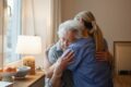 A caregiver and older adult share an embrace, symbolizing the human connection technology should protect, not replace.